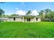 A view of the home's rear, featuring a covered patio and expansive backyard with lush green lawn at 10675 Sw 69Th Ter, Ocala, FL 34476