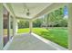 View of covered patio with ceiling fan, concrete floor, and lush backyard at 10675 Sw 69Th Ter, Ocala, FL 34476