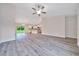 Bright living room with modern gray flooring, ceiling fan, and view into the kitchen and backyard at 10675 Sw 69Th Ter, Ocala, FL 34476