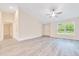Well-lit living room with gray flooring, ceiling fan, a large window, and a white front door at 10675 Sw 69Th Ter, Ocala, FL 34476