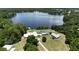 Expansive aerial view highlighting the lakefront home, pool, lush greenery, and surrounding trees at 10893 Se 141 Avenue Rd, Ocklawaha, FL 32179