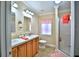 Well-lit bathroom with dual sinks, vanity, shower, and ceramic tile flooring at 10893 Se 141 Avenue Rd, Ocklawaha, FL 32179