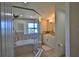 Bright bathroom showcasing a shower, soaking tub, tiled floor, and a window with shutters at 10893 Se 141 Avenue Rd, Ocklawaha, FL 32179
