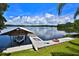 Scenic view of the lake from the backyard with a boat dock, boat, and lawn at 10893 Se 141 Avenue Rd, Ocklawaha, FL 32179