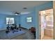 A bright exercise room features a weight set, laminate floors, a ceiling fan, and a door leading to the bathroom at 10893 Se 141 Avenue Rd, Ocklawaha, FL 32179