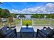 Stunning lake view from the deck featuring a table and chairs, set against a backdrop of lush greenery and a vibrant blue sky at 10893 Se 141 Avenue Rd, Ocklawaha, FL 32179