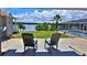 Spectacular lake view from the patio with wooden rocking chairs facing a green lawn, a screened-in pool, and a beautiful lake at 10893 Se 141 Avenue Rd, Ocklawaha, FL 32179