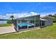 A screened-in pool and attached patio overlooks the lake and includes a lounge space with wicker furnishings at 10893 Se 141 Avenue Rd, Ocklawaha, FL 32179