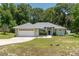 A well-maintained front yard featuring mature landscaping, manicured lawn, and an attached two-car garage at 11645 Mallard Ct, Dunnellon, FL 34432