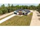 An aerial view of a modern farmhouse with a long driveway and lush greenery in the background at 12251 Sw 67Th Ln, Ocala, FL 34481