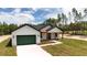A modern farmhouse featuring white siding, a dark roof, green garage door, and a long, white driveway at 12251 Sw 67Th Ln, Ocala, FL 34481