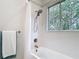 Bathtub and shower with white subway tile, mosaic accent, and window to exterior at 15620 Nw 112Th Ave, Reddick, FL 32686