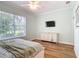 Bedroom with a large window, hardwood floors, and a TV above the dresser at 15620 Nw 112Th Ave, Reddick, FL 32686