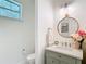 Charming powder room with a green vanity, gold framed mirror, and floral accents at 15620 Nw 112Th Ave, Reddick, FL 32686