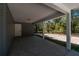 Spacious covered carport with a concrete floor and white support beams, and a rear door at 16615 Se 63Rd Ln, Ocklawaha, FL 32179