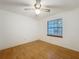 A simple, clean bedroom featuring light-colored wood floors and a ceiling fan, bathed in natural light from a window at 16621 Se 57Th Pl, Ocklawaha, FL 32179