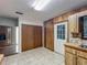 Kitchen featuring stainless steel refrigerator, wood paneling, cabinetry, and a white paneled door at 16621 Se 57Th Pl, Ocklawaha, FL 32179