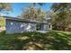 An open backyard featuring gray siding, a sliding glass door, and lush greenery at 17009 Se 60Th St, Ocklawaha, FL 32179