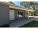 A well-lit covered front porch with a white door, gray siding, and neat landscaping at 17009 Se 60Th St, Ocklawaha, FL 32179