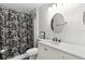 Well-lit bathroom features a round mirror and a floral shower curtain at 18 Banyan Pass, Ocala, FL 34472