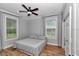 Simple bedroom design with wood-look floors, ceiling fan, curtains, two windows and a bed at 300 Se Highway 42, Summerfield, FL 34491