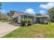 Charming home exterior featuring a well-maintained lawn, a covered porch, and a spacious driveway at 300 Se Highway 42, Summerfield, FL 34491