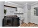 Modern laundry room featuring a front load washer, dryer, utility sink, storage, and wood-look tile floors at 300 Se Highway 42, Summerfield, FL 34491