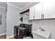 Bright laundry room featuring front load washer and dryer set, white shaker cabinets, and a utility sink at 300 Se Highway 42, Summerfield, FL 34491