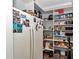 Well-organized pantry with white shelving next to a refrigerator filled with food and storage containers at 300 Se Highway 42, Summerfield, FL 34491