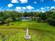Aerial shot showcasing a home with a screened-in porch, nestled amid lush greenery, overlooking a dock on a lily pad-filled lake at 3000 Pine Grove Ln, Lady Lake, FL 32159
