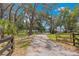 A long driveway with a wooden gate leads to the home, which is surrounded by mature trees and lush landscaping at 3000 Pine Grove Ln, Lady Lake, FL 32159
