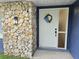 A white front door with a wreath and a stone accent wall creates an inviting entrance at 327 Se 50Th Ave, Ocala, FL 34471