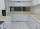 Well-lit kitchen showcasing white cabinets, countertops, and appliances, open to the living space at 3856 Ne 17Th Street Cir, Ocala, FL 34470