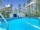 The above-ground pool sits next to the metal building and has mature trees surrounding it at 4258 Sw Zinnia Ct, Dunnellon, FL 34431