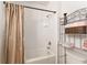 Clean bathroom featuring shower-tub combo, white tiled walls, and a functional shelving unit at 6646 Sw 64Th Ave, Ocala, FL 34476