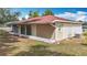 Tan home exterior with white trim, slider doors, and a red roof, nestled on a grassy lot, with a white cinderblock foundation at 70 Sapphire Rd, Ocala, FL 34472