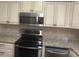 Stainless steel microwave and range above granite countertops and white cabinets at 9722 Sw 95Th Ct # C, Ocala, FL 34481