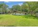 Charming exterior view of a well-maintained single-story home surrounded by a lush green lawn and mature trees at 12178 Palmetto Way, Dunnellon, FL 34432