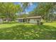Exterior view of a cozy single-story home with a well-maintained lawn and mature trees providing ample shade at 12178 Palmetto Way, Dunnellon, FL 34432