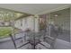 Enclosed porch with outdoor dining set, sliding glass doors leading indoors, and screens for insect protection at 12178 Palmetto Way, Dunnellon, FL 34432
