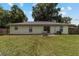 View of the house from a spacious backyard with a grassy area and a mature shade tree at 1245 Nw 67Th Pl, Ocala, FL 34475