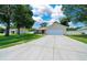 Home exterior featuring a two-car garage, a well-manicured lawn, and mature shade trees at 1553 Ne 161St Pl, Citra, FL 32113