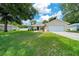 Exterior of a beige home with a well-manicured lawn and a long concrete driveway at 1553 Ne 161St Pl, Citra, FL 32113