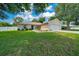 Exterior of a beige home with a well-manicured lawn and a long concrete driveway at 1553 Ne 161St Pl, Citra, FL 32113