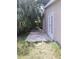 Side view of a home with a small concrete patio surrounded by lush greenery and trees at 2426 Maple Ave, Sanford, FL 32771