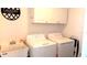 Bright laundry room featuring a utility sink, modern washer, dryer, and ample white cabinet storage at 2550 Sw Ivy Pl, Dunnellon, FL 34431
