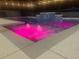 Captivating pool view with illuminated pink fountain jets and a tiled waterfall feature at night at 3223 Sw 41St Ave, Ocala, FL 34474