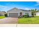 Single-story home with a brick driveway, tidy landscaping and a charming pink front door at 358 Irving Bend Dr, Groveland, FL 34736