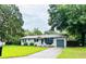 Single-story home with a gray exterior, dark shutters, and a large tree in the front yard at 3610 Sw 25Th Pl, Ocala, FL 34474