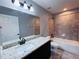 Bathroom featuring dark wood vanity with granite countertop, a bathtub, and tiled shower walls at 5320 Sw 128Th Pl, Ocala, FL 34473